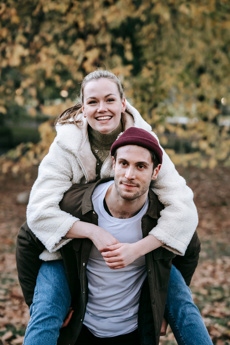 Cheerful girlfriend smiling and piggyback riding on happy boyfriend