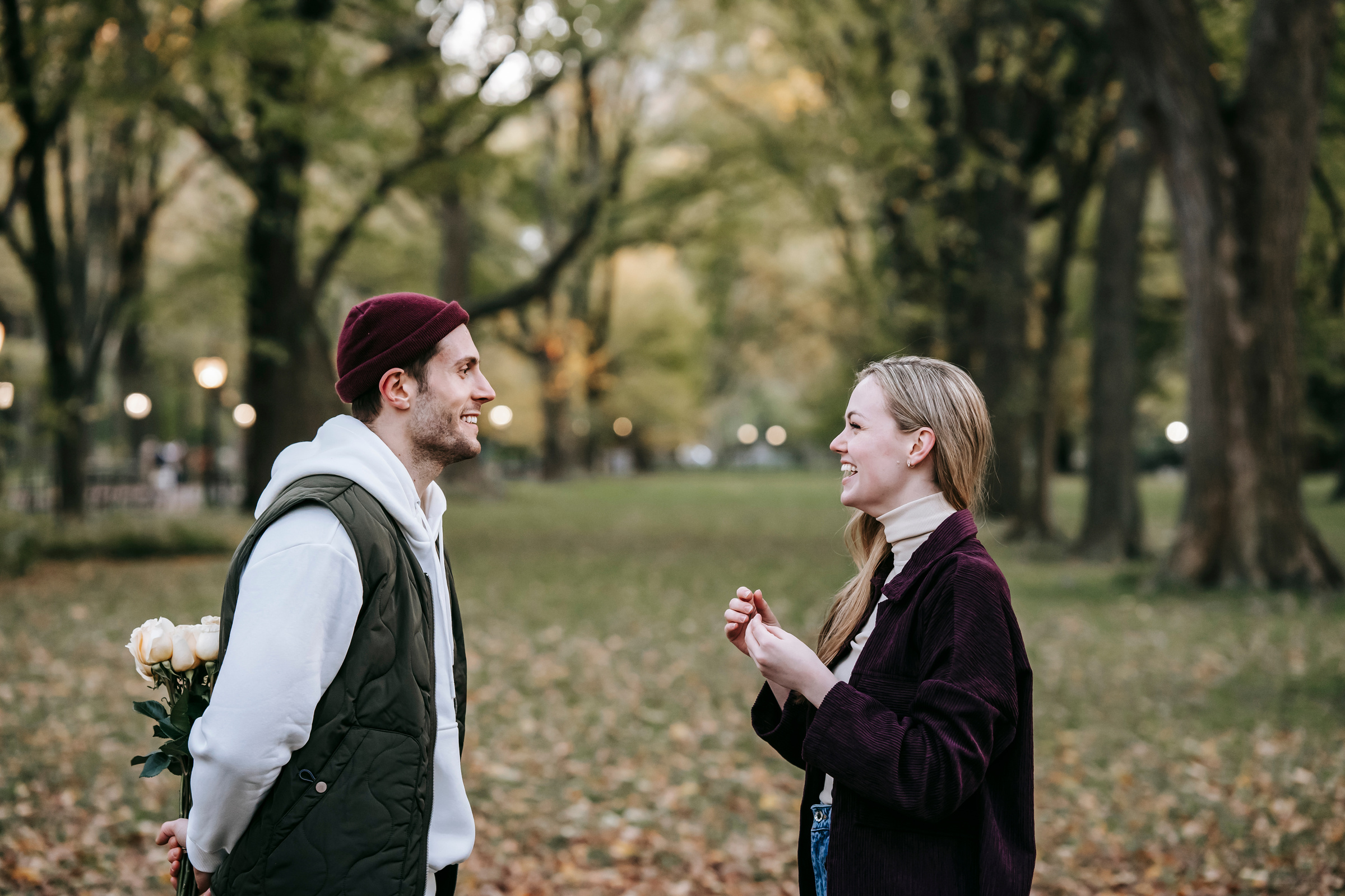 Happy couple standing in street with flowers near trees